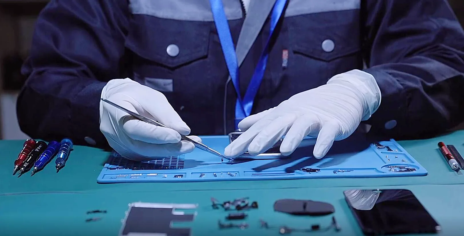 Technician repairing a mobile device at a workbench